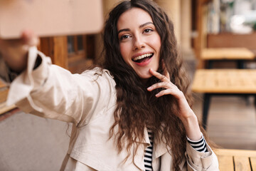 Wall Mural - Image of happy woman taking selfie photo on cellphone and smiling