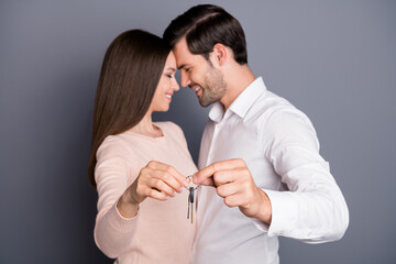 Photo beautiful lady handsome guy in love hold keys chain relocation concept buy flat house just married couple owners happy together wear shirt pullover pants isolated grey color background