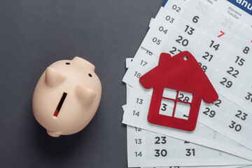 Wall Mural - Monthly Budget. Paying rents for housing. Piggy bank, house figurine with monthly calendar on gray background. Top view