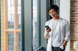 © Drobot Dean - Image of young asian man wearing earphones using cellphone in office