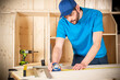 © stockphoto-graf - young male carpenter with beard and metal tape measure at work. measuring wood plank  woodworking construction tool concept furniture making diy background