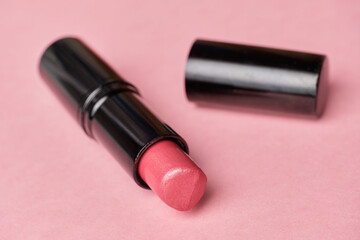 Pink lipstick open on the background close up.