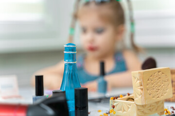 Wall Mural - girl 4 years old makes makeup mom's makeup. focus on cosmetics, girl in blur