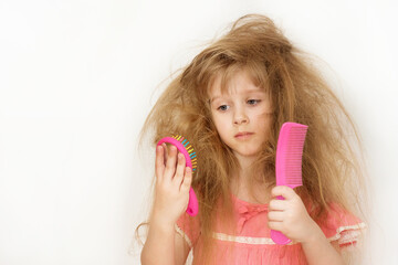 Wall Mural - a little girl with unruly, tangled long hair in a pink dress on a white background tries to comb it