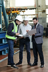 Portrait of a 3 men in a airplane manufactory. Two company managers and one factory worker deciding future plans. Business solution. 