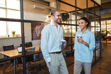 Wall Mural - Photo of multinational joyful colleagues talking and drinking coffee