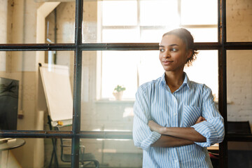 Wall Mural - Photo of joyful african american woman smiling while leaning on glass