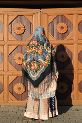 Russian bohemian girl in vintage Pavlovo Posad shawl and old carved gate of wooden traditional national rural house in Suzdal city, Russia. Russian folk style in architecture, architectural fashion