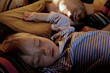 © Gargonia - Cute toddler son and his father sleeping together on bed in bedroom at home. Real lifestyle family photo taken early morning. Fathers day concept.