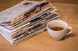 selective focus of the drunk cup of tea stacking newspapers folded place on wooden table