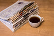 selective focus of the cup of tea stacking newspapers folded place on wooden table