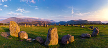 A Panorama Of Castlerigg Stone Circle Looking South At Sunset The Dusk Light Painting The Stones And Casting Their Shadows Across The Grass, Sheep Graze In The Circle Wispy White Clouds Fleck The Sky