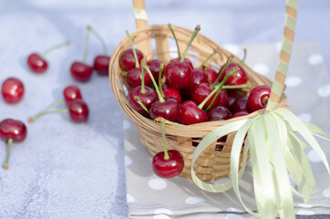 Ripe juicy cherry lies on a table and in a wicker basket. The concept of home gardening.