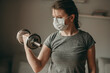 © lesia17 - Young woman trains biceps dumbbell with medical surgical mask. Sport at home on quarantine. Coronavirus, illness, infection, protection, bandage.
