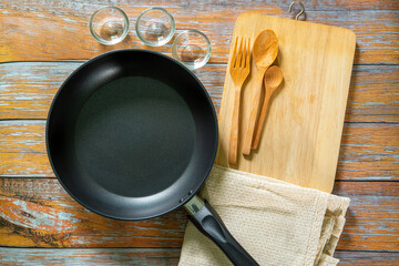 Cast iron pan and other kitchen utensils on a dark brown aged background, top view