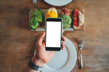 Top view of man’s hand holding modern smartphone with blank screen with copy space for text message or design, Mock up of cellphone, Ordering food online concept, Delivery Service