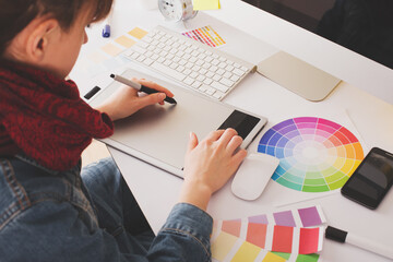 Wall Mural - Young Handsome Graphic designer using graphics tablet to do his work at desk