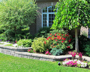 Landscape design with multiple levels and stone retaining wall for flower beds and hidden downspout through garden.