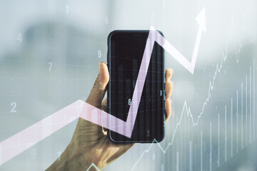 Double exposure of abstract creative financial chart with upward arrow and hand with cell phone on background, research and strategy concept