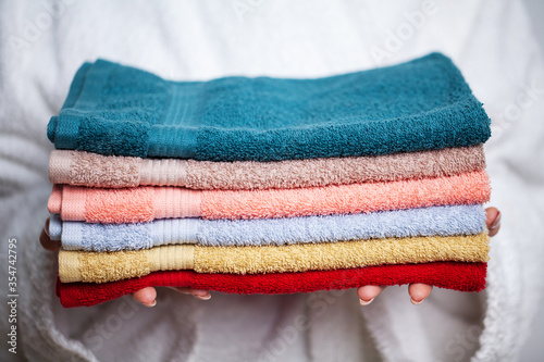 Fotomural Woman in a white coat holding a stack of colored towels