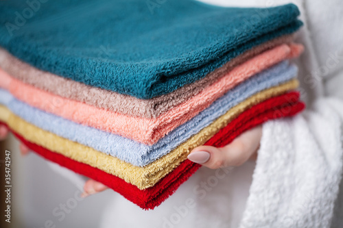 Fotografía Woman in a white coat holding a stack of colored towels