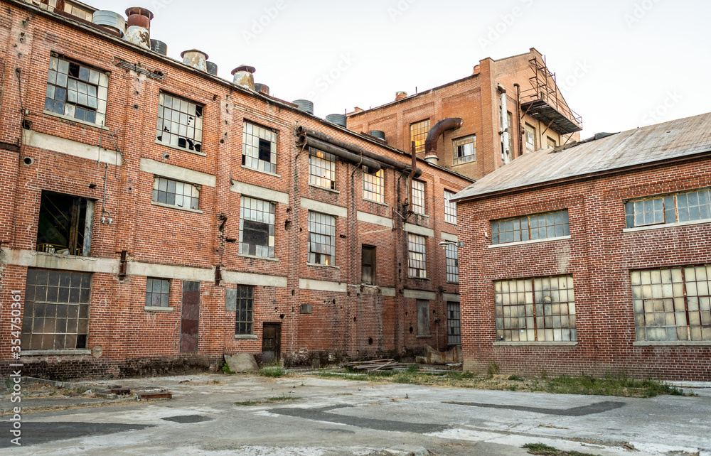 Abandoned multi-story brick factory building with broken glass windows ...
