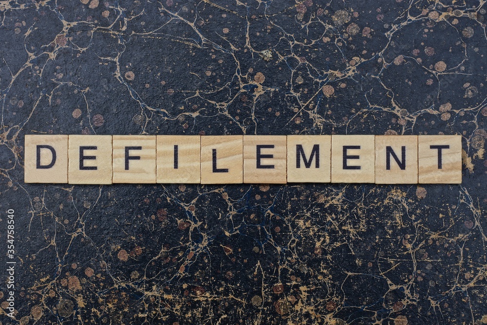 word defilement from wooden letters in black font on a brown shabby ...