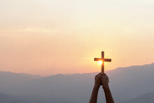Silhouette Human Hand Holding Christian Cross For Worshipping God At Sunset Sky Background. Christian, Christianity, Religion Copy Space Background.