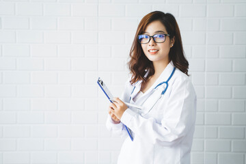 Medical health clinic beautiful Asian doctor working using laptop stethoscope diagnosing patient analysis writing on form contract healthcare provider service insurance busy in modern office desk