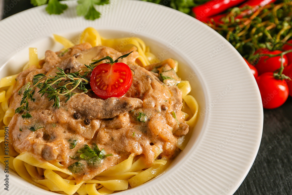 Plate with tasty beef stroganoff and pasta, closeup
