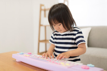 Sticker - おもちゃのキーボードを弾いて遊ぶ3歳の女の子