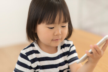 Sticker - 自宅の居間でスマートフォンを見る3歳の女の子