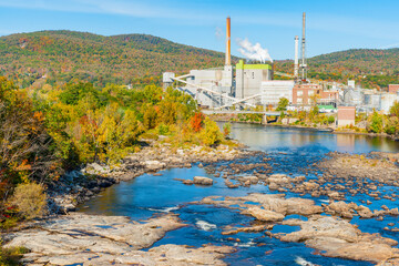 Canvas Print - Idyllic environment and stream and Rumford Falls surrounded by beautiful autumn foliage colors with visual conflict of industrial building in pristine environment.