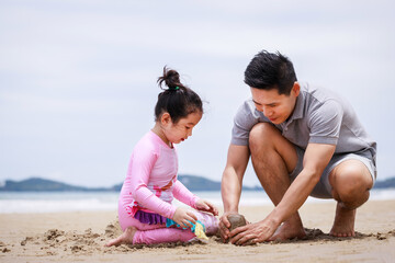 Happy family. Happy vacation holiday. Happy father and daughter are building a sandcastle on the tropical beach and have fun together in summer. Relaxation in vacation in the summer concept.