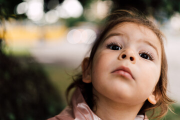 Toddler girl close up portrait. Surprised child outdoors in park. Camping concept. 