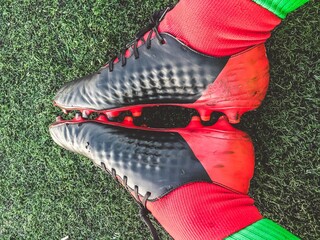 Poster - Overhead closeup shot of red and black football shoes on the grass