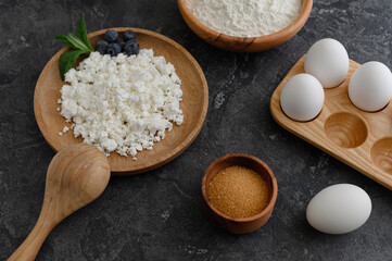 Cottage cheese, flour, eggs, sugar. Dark background.