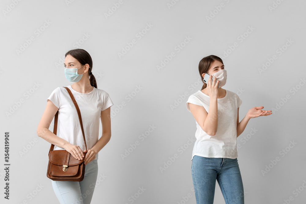 Young women on light background. Concept of social distance during coronavirus epidemic