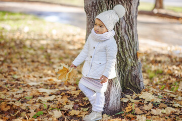 Child in autumn orange leaves.