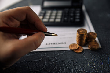 The concept of finance and business. Contract, calculator, money and pen on a table. Conclusion of a profitable transaction.