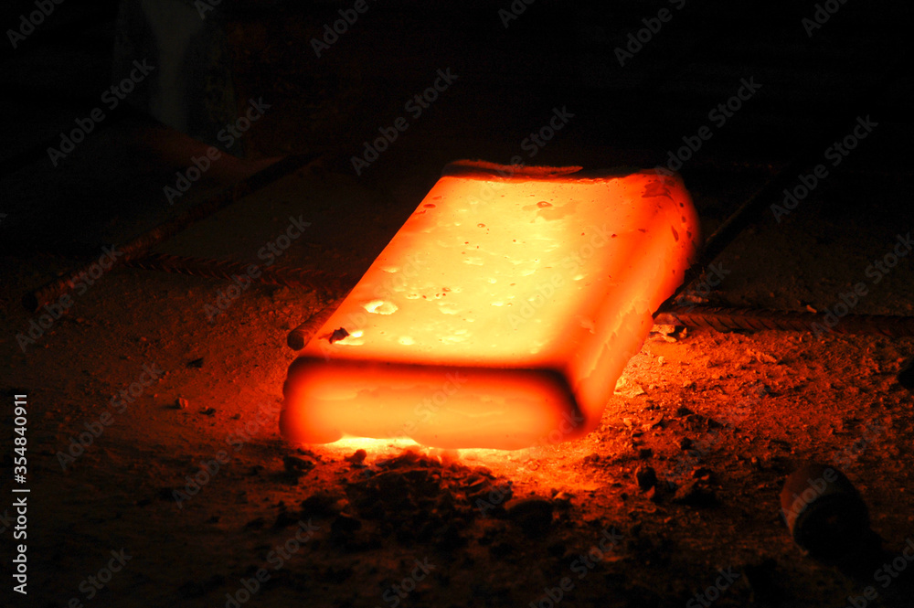 Lingote de metal al rojo vivo sobre malla metálica en terreno arenoso Stock  Photo | Adobe Stock