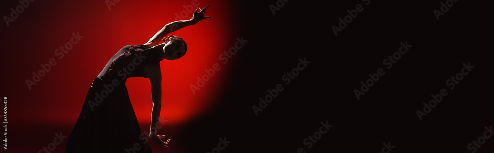 panoramic orientation of young woman dancing flamenco on red and black - obrazy, fototapety, plakaty 