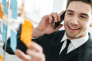 Wall Mural - Image of smiling businessman talking on cellphone while working