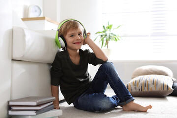 Canvas Print - Cute little boy with headphones listening to audiobook at home