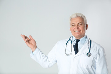 Poster - Portrait of senior doctor against light background. Medical service