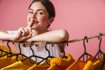 Poster - Photo of woman gesturing silence sing while leaning on clothes rack