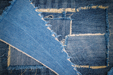 Destroyed torn denim blue jeans fabric frame on blue jeans background. Worn Jeans Casual Double Color patch Denim.