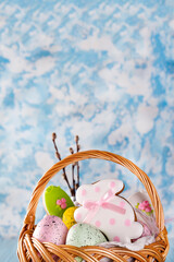 Sticker - Easter cookies, bunnies and Multicolored Easter eggs in a basket on light blue background