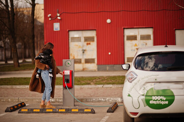 Wall Mural - Young mother with child charging electro car at the electric gas station.