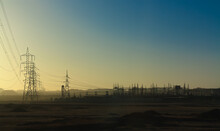 A Power Station Far Out In The Desert In Southern Egypt. The Electricity Pylons Soar Into The Sky. In The Background Are The Mountains In Front Of The Desert.